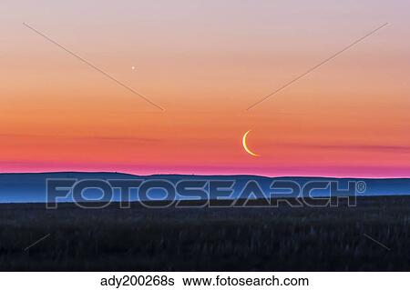 Stock Photograph - Moon and Venus rising over the flat prairie horizon of Alberta, Canada.. Fotosearch
