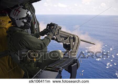 Naval Aircrewman fires a. 50-caliber machine gun from a MH-60S Knighthawk. View Large Photo Image Picture - Naval Aircrewman fires a. 50-caliber machine gun from a MH-60S Knighthawk.. Fotosearch