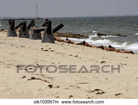 Navy SEALs crawl up the beach to set simulated explosives charges. View Large Photo Image Picture - Navy SEALs crawl up the beach to set simulated explosives charges.. Fotosearch