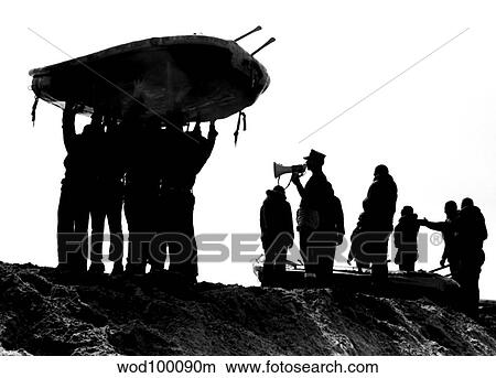 Picture - Navy SEALs hold an inflatable boat over their heads as the instructor shouts commands over a megaphone.. Fotosearch