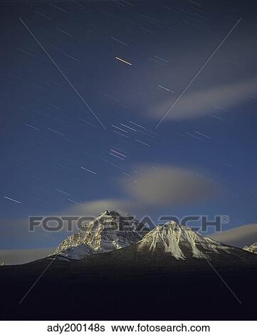 Stock Photograph - Orion star tails over Mt. Temple, Banff National Park, Alberta, Canada. . Fotosearch