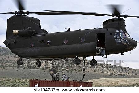 Personnel attach a storage container to a CH-47 Chinook helicopter. View Large Photo Image Picture - Personnel attach a storage container to a CH-47 Chinook helicopter.. Fotosearch