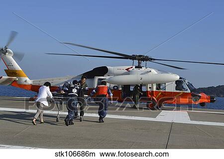 Personnel transport a simulated victim to a helicopter during a casualty drill. View Large Photo Image Picture - Personnel transport a simulated victim to a helicopter during a casualty drill.. Fotosearch