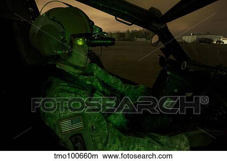 Pilot equipped with night vision goggles in the cockpit of an Apache helicopter. View Large Photo Image Picture - Pilot equipped with night vision goggles in the cockpit of an Apache helicopter.. Fotosearch