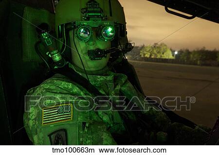 Pilot equipped with night vision goggles in the cockpit of an Apache helicopter. View Large Photo Image Picture - Pilot equipped with night vision goggles in the cockpit of an Apache helicopter.. Fotosearch