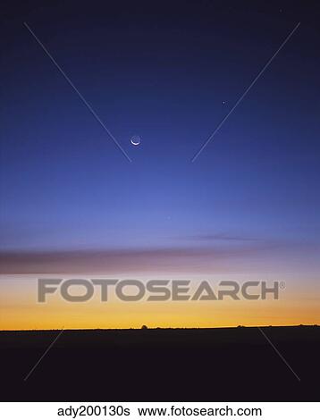 Stock Photograph - Pre-dawn sky with waning crescent moon, Jupiter at top, and Mercury at lower center.. Fotosearch