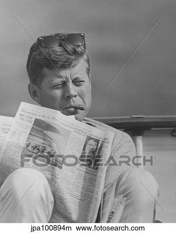 President John F. Kennedy smoking a cigar and reading the newspaper. View Large Photo Image Picture - President John F. Kennedy smoking a cigar and reading the newspaper.. Fotosearch