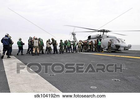 Sailors and Marines load supplies onto a HH-60H Seahawk. View Large Photo Image Picture - Sailors and Marines load supplies onto a HH-60H Seahawk.. Fotosearch