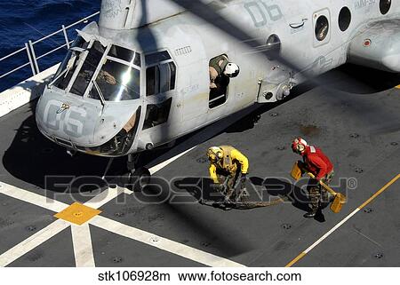 Sailors chock and chain a CH-46E Sea Knight helicopter. View Large Photo Image Picture - Sailors chock and chain a CH-46E Sea Knight helicopter.. Fotosearch