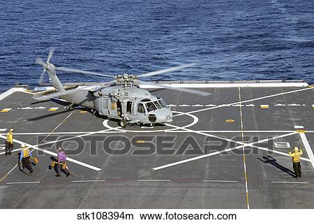 Sailors move in to chock and chain an MH-60S Sea Hawk helicopter. View Large Photo Image Picture - Sailors move in to chock and chain an MH-60S Sea Hawk helicopter.. Fotosearch