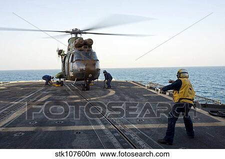 Sailors place chocks and chains on a French Army SA 380 Puma helicopter. View Large Photo Image Picture - Sailors place chocks and chains on a French Army SA 380 Puma helicopter.. Fotosearch