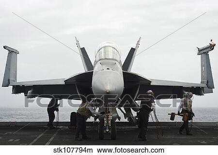 Sailors remove chocks and chains from an F/A-18F Super Hornet. View Large Photo Image Picture - Sailors remove chocks and chains from an F/A-18F Super Hornet.. Fotosearch