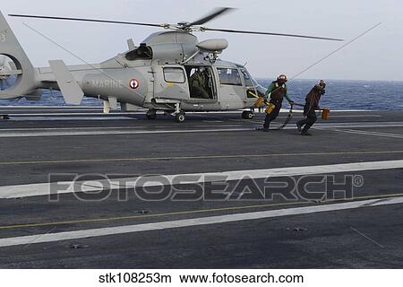 Sailors remove chocks and chains from an AS565 Panther helicopter. View Large Photo Image Picture - Sailors remove chocks and chains from an AS565 Panther helicopter.. Fotosearch