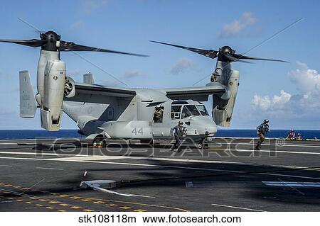 Picture - Sailors run to safety after they chock and chain a MV-22 Osprey.. Fotosearch