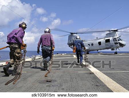 Sailors rush to chock and chain a CH-46E Sea Knight helicopter. View Large Photo Image Picture - Sailors rush to chock and chain a CH-46E Sea Knight helicopter.. Fotosearch