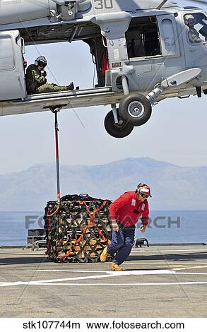 Seaman hooks a pallet to an MH-60S Sea Hawk helicopter. View Large Photo Image Picture - Seaman hooks a pallet to an MH-60S Sea Hawk helicopter.. Fotosearch