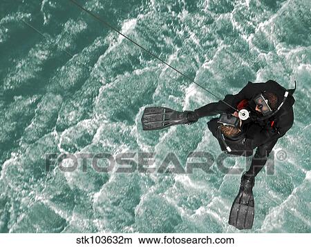 Search and Rescue swimmers are hoisted into an MH-60S Seahawk over the Persian Gulf. View Large Photo Image Picture - Search and Rescue swimmers are hoisted into an MH-60S Seahawk over the Persian Gulf.. Fotosearch