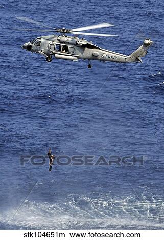 Picture - Search and rescue swimmers being hoisted into a helicopter.. Fotosearch
