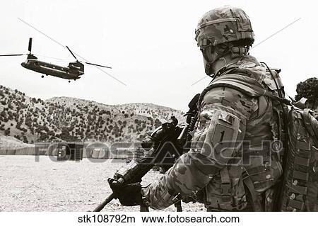 Soldier assigned to the 1st Infantry Division awaits an incoming CH-47 Chinook. View Large Photo Image Picture - Soldier assigned to the 1st Infantry Division awaits an incoming CH-47 Chinook.. Fotosearch