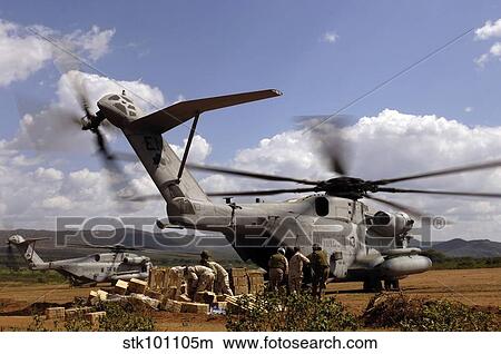 Picture - Soldiers and sailors help pile boxes of food and water off a CH-53E helicopter.. Fotosearch