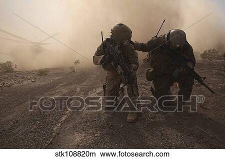 Soldiers brace for the impact of a cloud of sand and rocks from a landing CH-53 Super Stallion. View Large Photo Image Picture - Soldiers brace for the impact of a cloud of sand and rocks from a landing CH-53 Super Stallion.. Fotosearch
