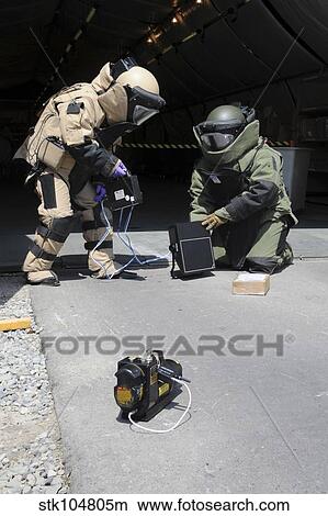Soldiers dressed in bomb suits examine a suspicious package. View Large Photo Image Picture - Soldiers dressed in bomb suits examine a suspicious package.. Fotosearch