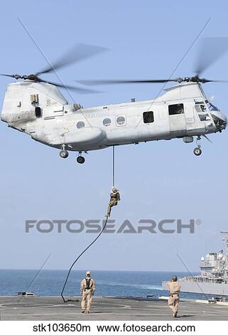 Soldiers fast rope from a CH-46E Sea Knight helicopter onto amphibious transport dock USS Denver. View Large Photo Image Picture - Soldiers fast rope from a CH-46E Sea Knight helicopter onto amphibious transport dock USS Denver.. Fotosearch