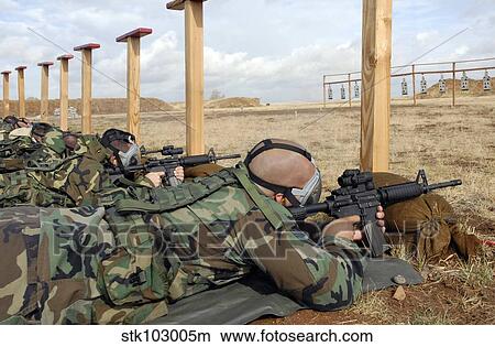 Soldiers sight M-4 rifles down range while wearing MCU-2 protective gas masks. View Large Photo Image Picture - Soldiers sight M-4 rifles down range while wearing MCU-2 protective gas masks.. Fotosearch