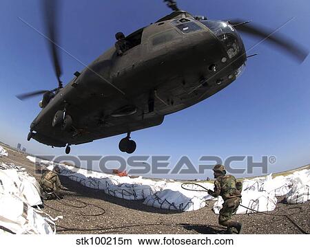 Specialists attach cargo hooks supporting large bags of sand to a CH-47 Chinook helicopter. View Large Photo Image Picture - Specialists attach cargo hooks supporting large bags of sand to a CH-47 Chinook helicopter.. Fotosearch