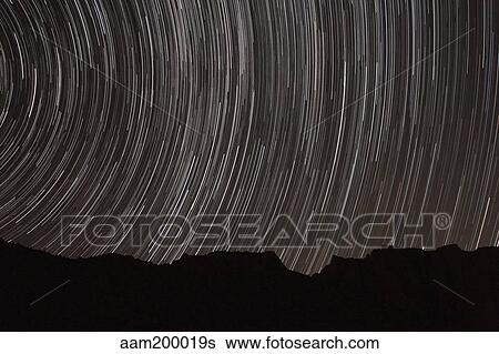 Stock Photograph - Star trails above a valley in the Firoozkooh area, Iran.. Fotosearch