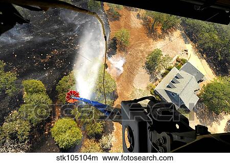 The Bambi Bucket attached to a CH-47 Chinook helicopter, dumps water on a wildfire in Texas. View Large Photo Image Picture - The Bambi Bucket attached to a CH-47 Chinook helicopter, dumps water on a wildfire in Texas.. Fotosearch