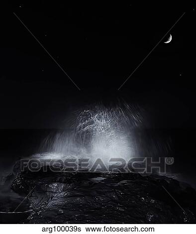 Stock Photograph - The crescent moon and waves splashing over rocks in Miramar, Argentina.. Fotosearch
