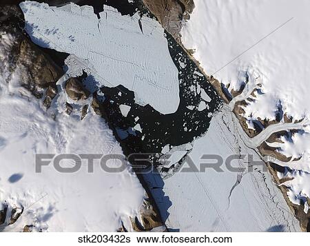 The ice island that calved off the Petermann Glacier in northwestern Greenland migrates down the fjord. View Large Photo Image Stock Photograph - The ice island that calved off the Petermann Glacier in northwestern Greenland migrates down the fjord.. Fotosearch
