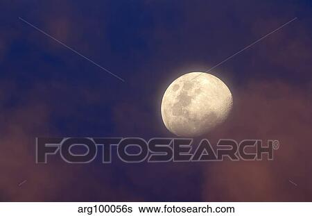 Stock Photograph - The moon between colorful clouds at sunset.. Fotosearch