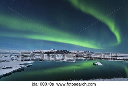 Stock Photograph - The northern lights dance over the glacier lagoon in Iceland.. Fotosearch