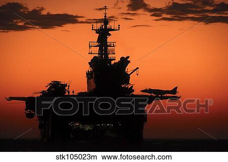 The setting sun silhouettes the amphibious assault ship USS Makin Island. View Large Photo Image Picture - The setting sun silhouettes the amphibious assault ship USS Makin Island.. Fotosearch