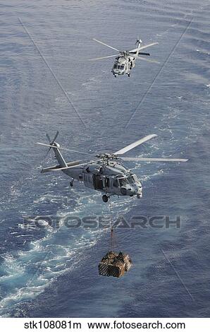 Two MH-60S Sea Hawk helicopters transport supplies. View Large Photo Image Picture - Two MH-60S Sea Hawk helicopters transport supplies.. Fotosearch