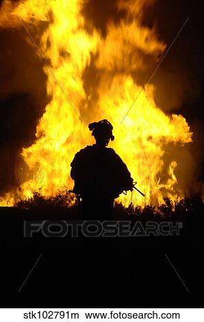 U. S. Army Sergeant monitors the flames of a fire around a canal. View Large Photo Image Picture - U. S. Army Sergeant monitors the flames of a fire around a canal.. Fotosearch