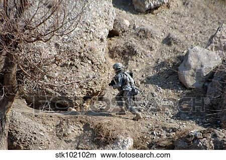 U. S. Army soldier walks up the side of a hill to look at caves. View Large Photo Image Picture - U. S. Army soldier walks up the side of a hill to look at caves.. Fotosearch