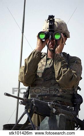 Picture - U. S. Army Specialist uses binoculars to scan the perimeter.. Fotosearch