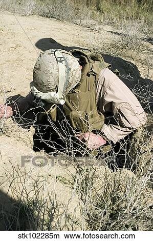 Picture - U. S. Marine jumps down a hole to search for a weapons cache.. Fotosearch