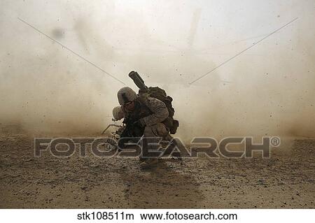U. S. Marine shields himself from dust being kicked up from a CH-53E Super Stallion. View Large Photo Image Picture - U. S. Marine shields himself from dust being kicked up from a CH-53E Super Stallion.. Fotosearch
