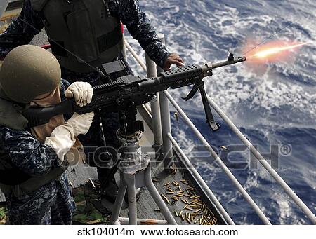 Picture - U. S. Navy Airman fires an M-240B machine gun aboard USS Essex.. Fotosearch