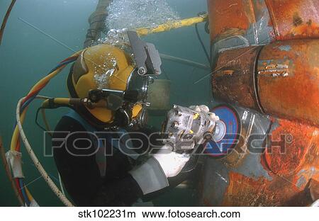 U. S. Navy Diver uses a grinder to file down a repair patch on the submerged bow of the USS Ogden. View Large Photo Image Picture - U. S. Navy Diver uses a grinder to file down a repair patch on the submerged bow of the USS Ogden.. Fotosearch