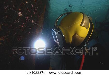 U. S. Navy Diver welds a repair patch on the submerged bow of the USS Ogden. View Large Photo Image Picture - U. S. Navy Diver welds a repair patch on the submerged bow of the USS Ogden.. Fotosearch