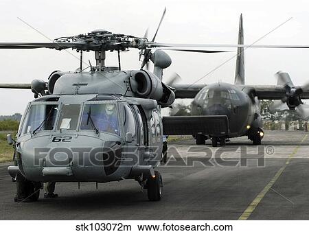 Picture - U. S. Navy SH-60B Seahawk helicopter and an Australian C-130 Hercules prepare for takeoff.. Fotosearch