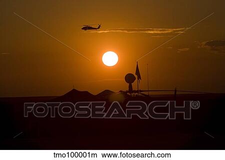 UH-60 Blackhawk flies over Camp Speicher airfield at sunset. View Large Photo Image Picture - UH-60 Blackhawk flies over Camp Speicher airfield at sunset.. Fotosearch