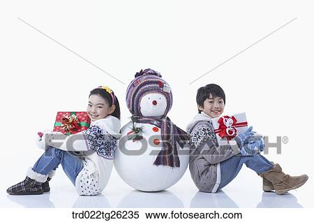 Stock Illustration - boy and girl holding the christmas present with a snowman. Fotosearch