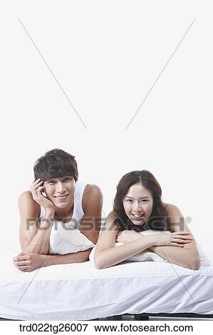 Stock Illustration - woman and guy relaxed on the bed with smile. Fotosearch