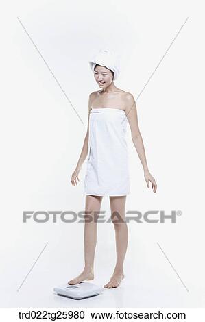 Clipart - woman in a towel measuring her weight. Fotosearch